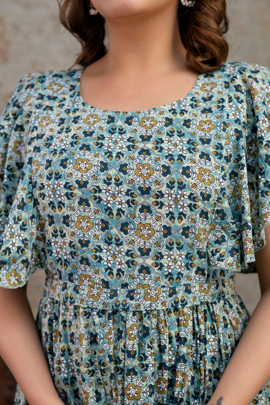 Close-up of round neckline, flutter sleeves and gathered waist on grey printed dress