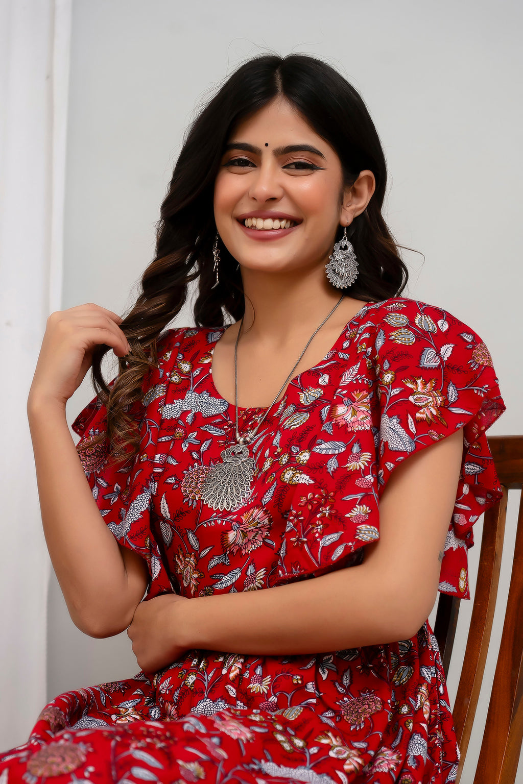 HENAL H391 Red floral maternity kurti, seated upper-body close-up showing round neckline, flutter sleeve and floral print.