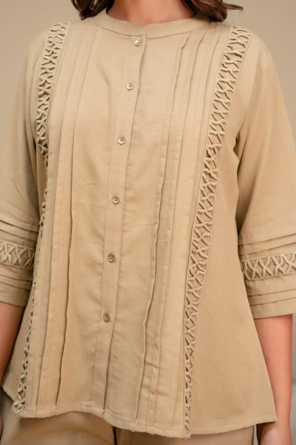 Close-up of beige top showing buttons, pintucks and cutwork trim
