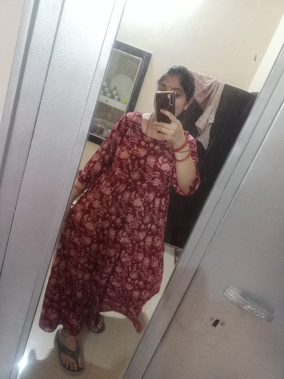 Mirror photo of a customer wearing a maroon floral dress