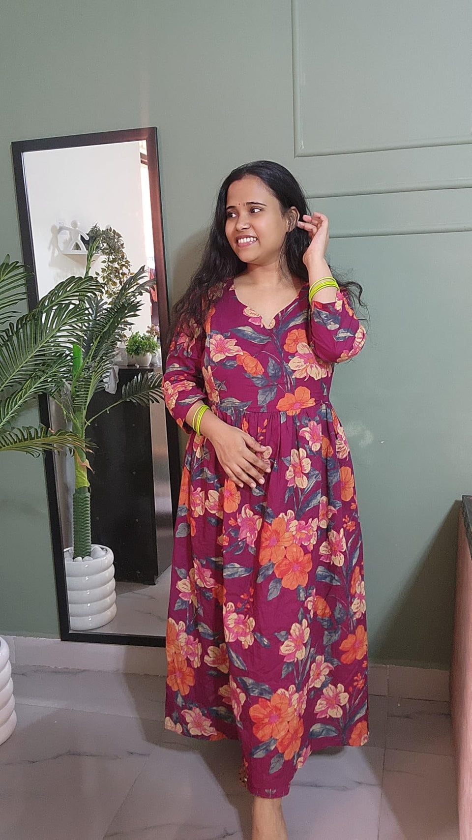 Customer wearing a plum dress with orange floral print indoors