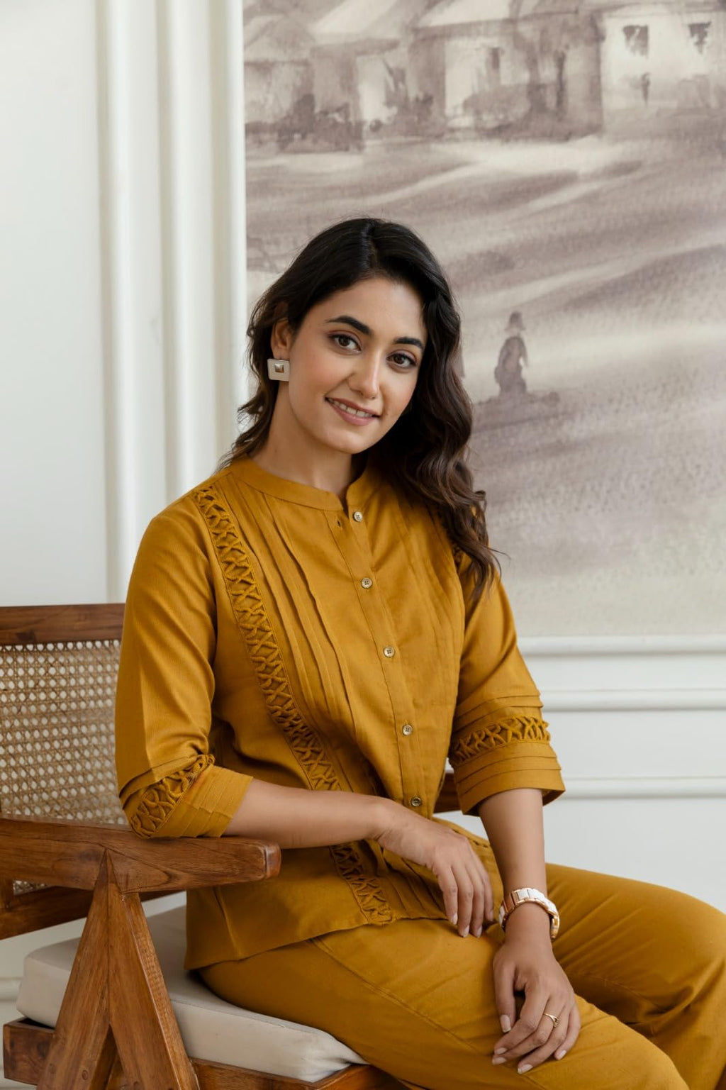 Seated view of mustard top and trousers with cutwork detailing