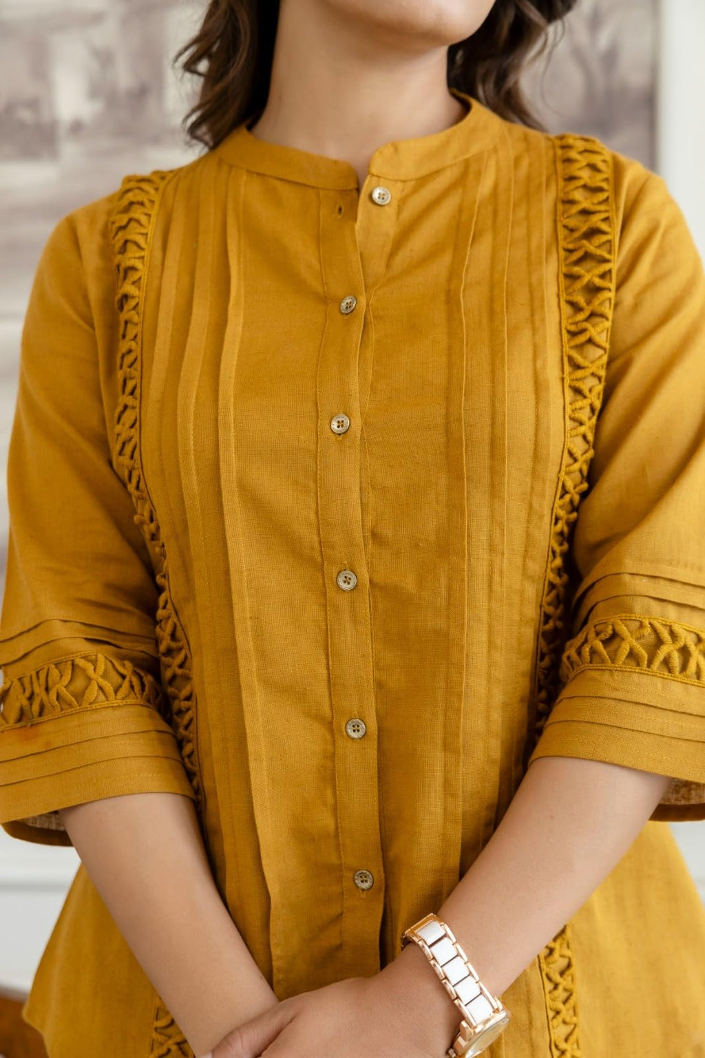 Close-up of mustard top showing buttons, pintucks and cutwork trim